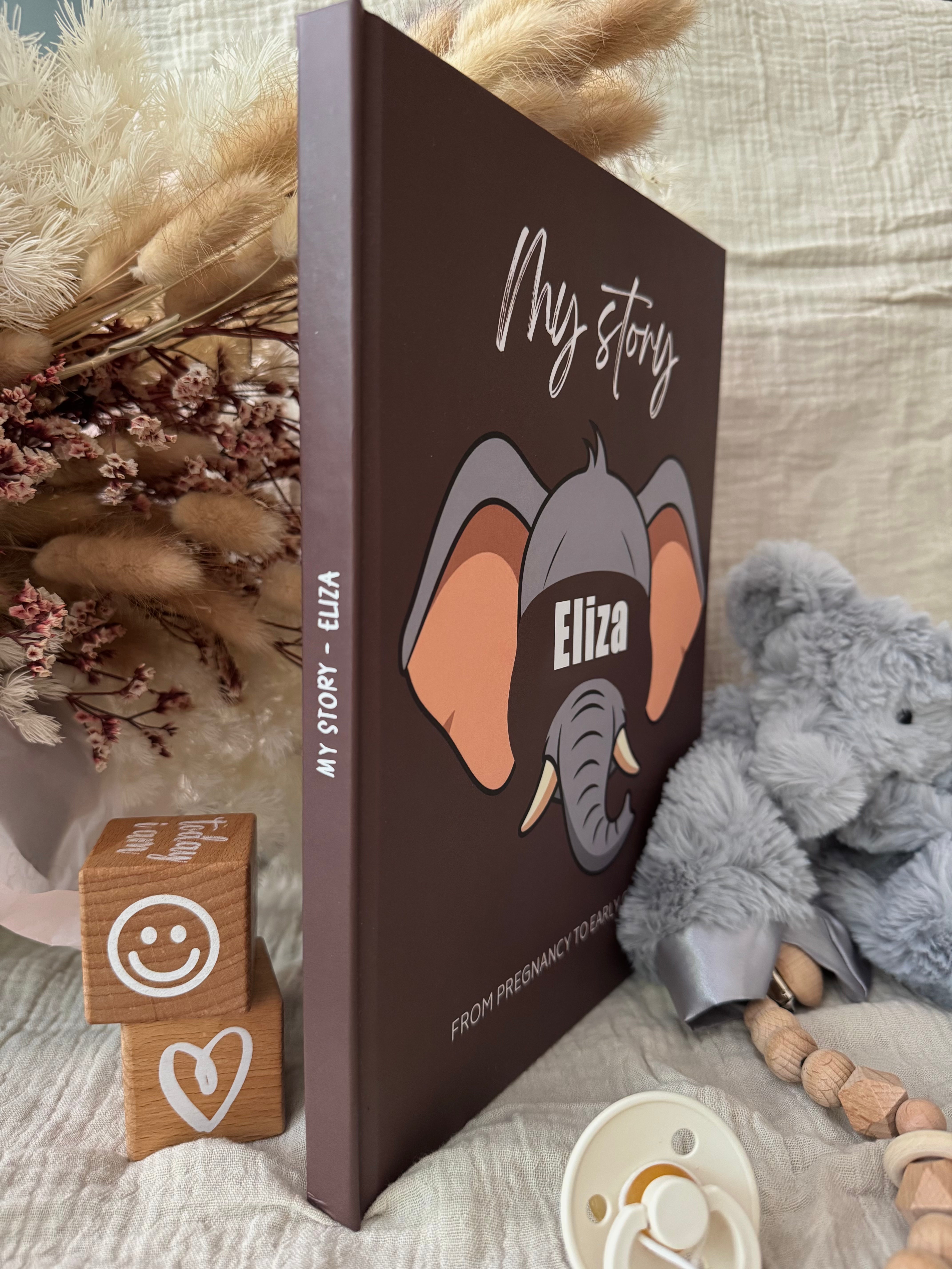 Exemple of personalized baby keepsake book titled 'My story' with a custom elephant illustration and the name 'Eliza' on the cover.